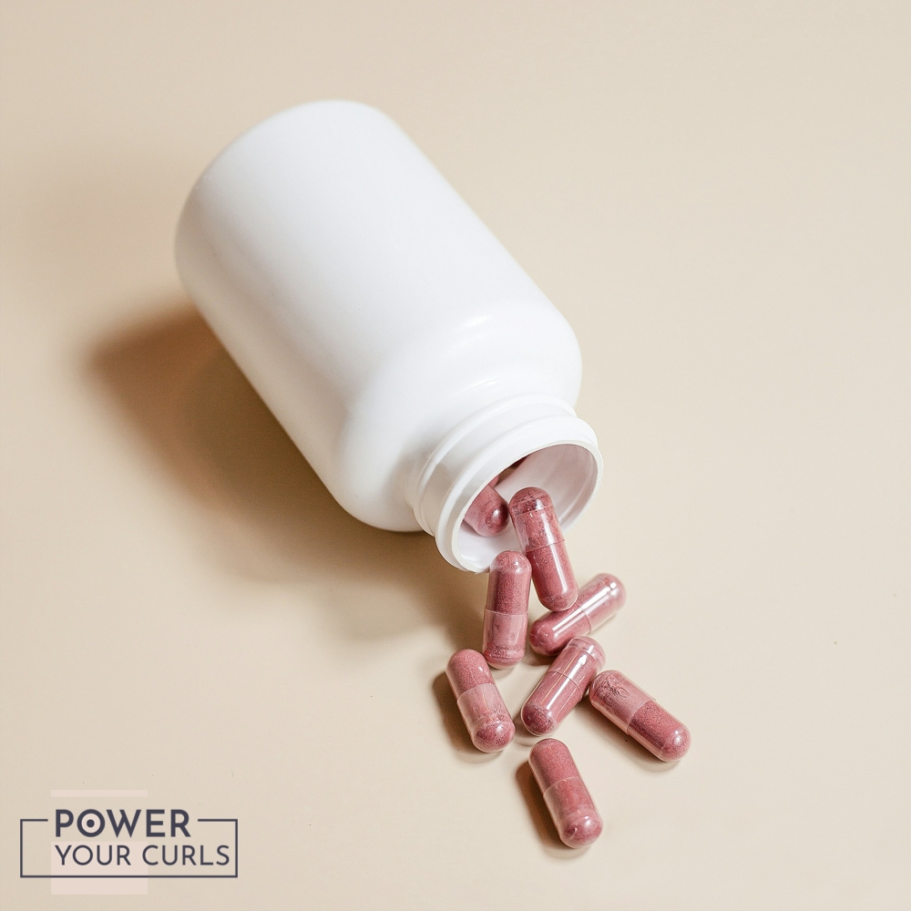 A bottle of iron supplements spilled out onto a beige colored background.